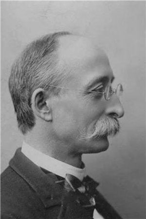 A head and shoulders portrait profile of a white man with spectacles, a large mustache, and a bow tie